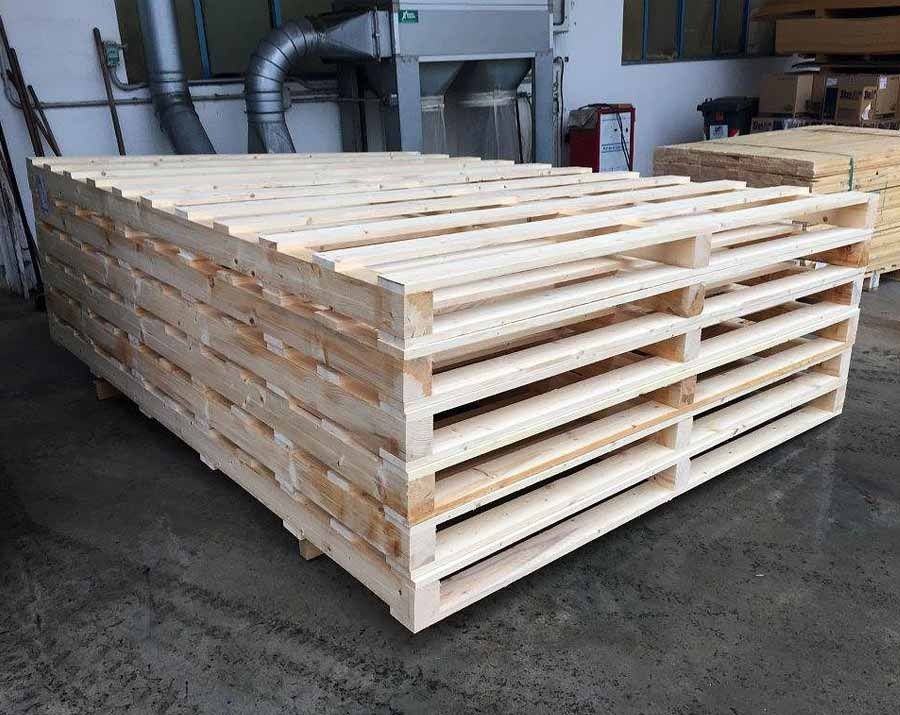 Una pila di pallet di legno appoggiati uno sopra l'altro sul terreno.