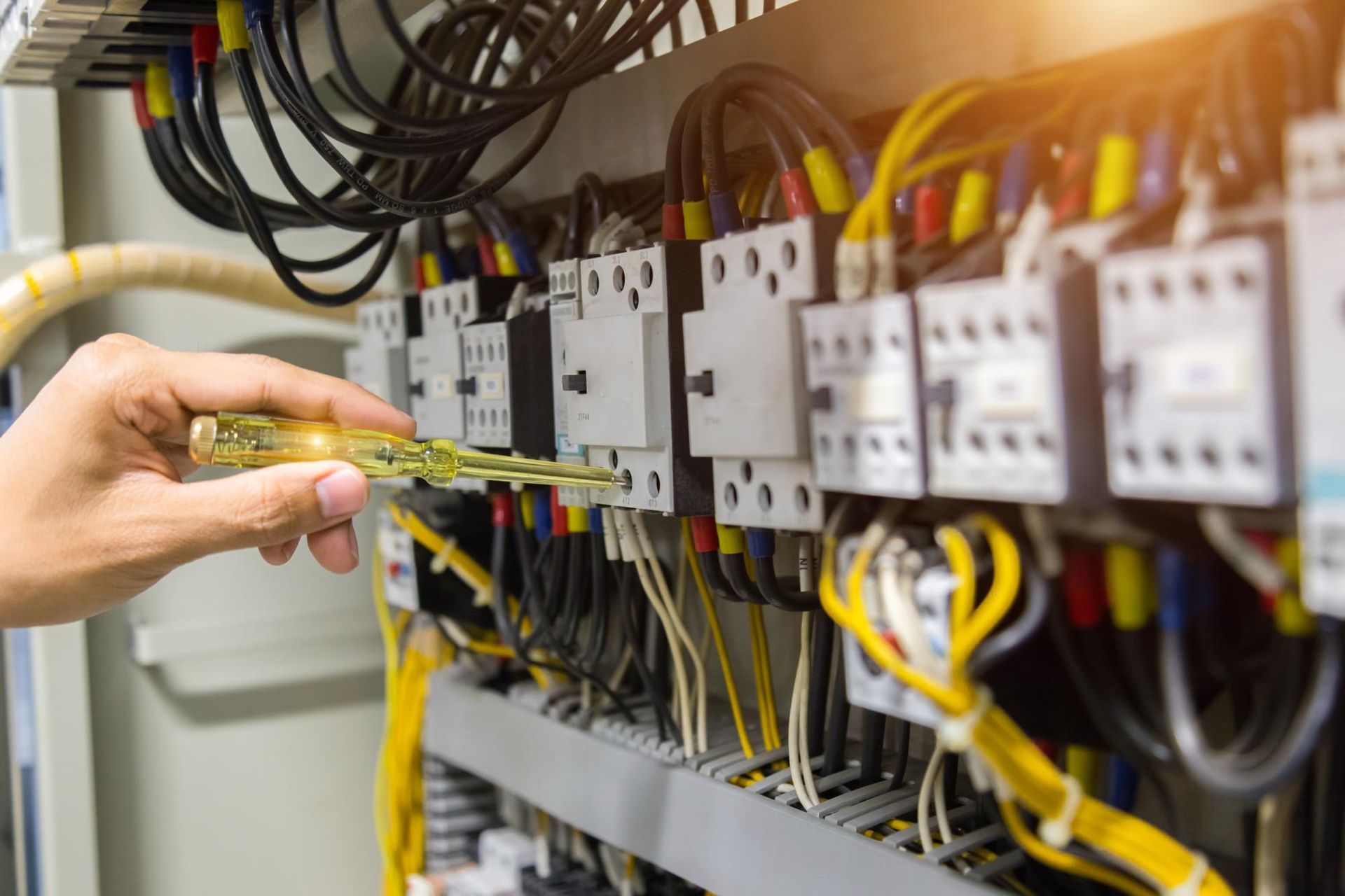 Technician testing electrical control panel wiring with a multimeter