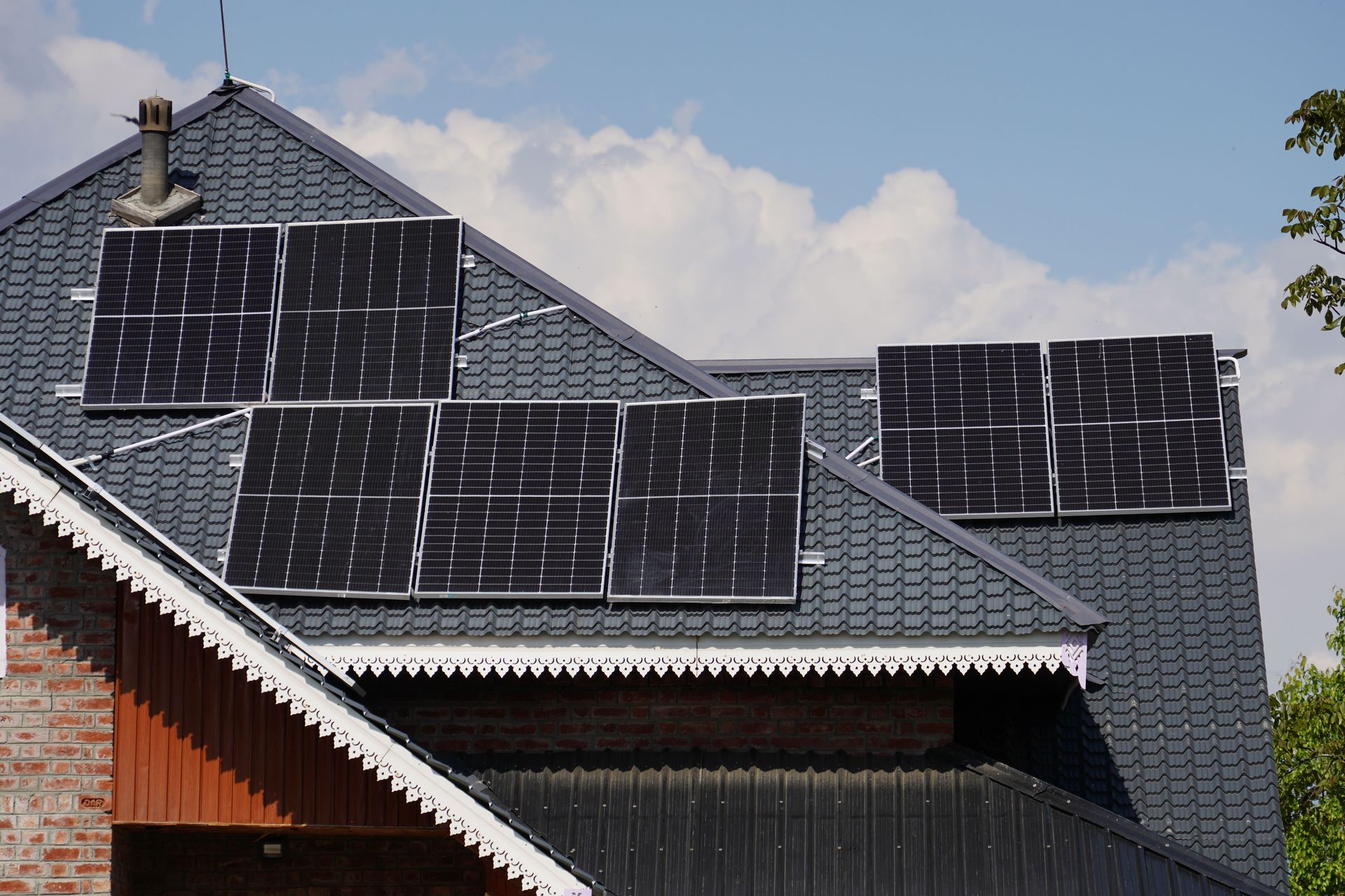 House roof covered with solar panels under a partly cloudy sky