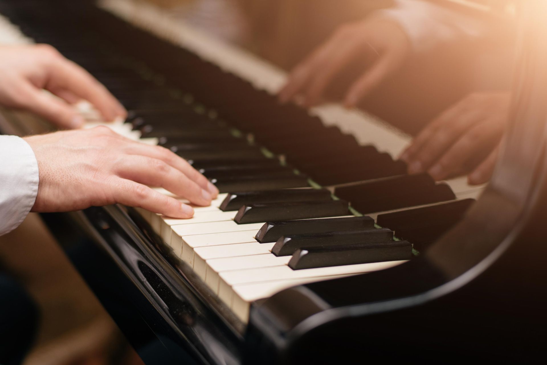 A man is playing a piano with his hands on the keys.