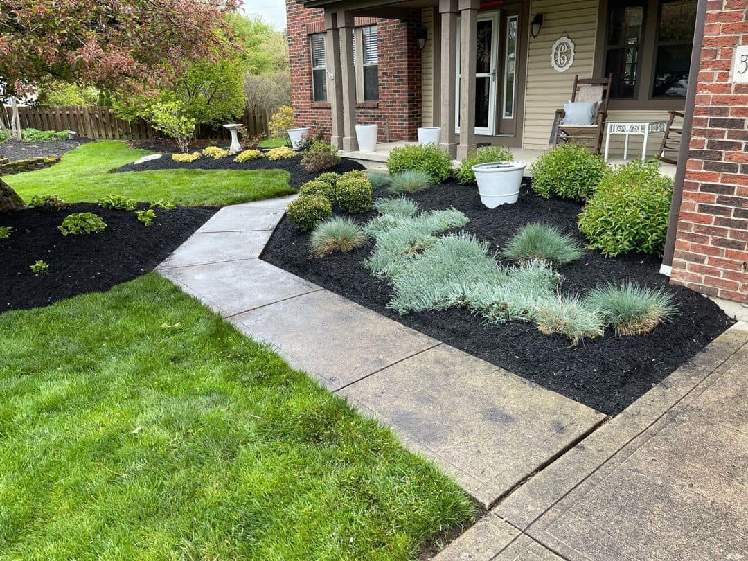 A brick house with a lush green lawn and a walkway leading to it.