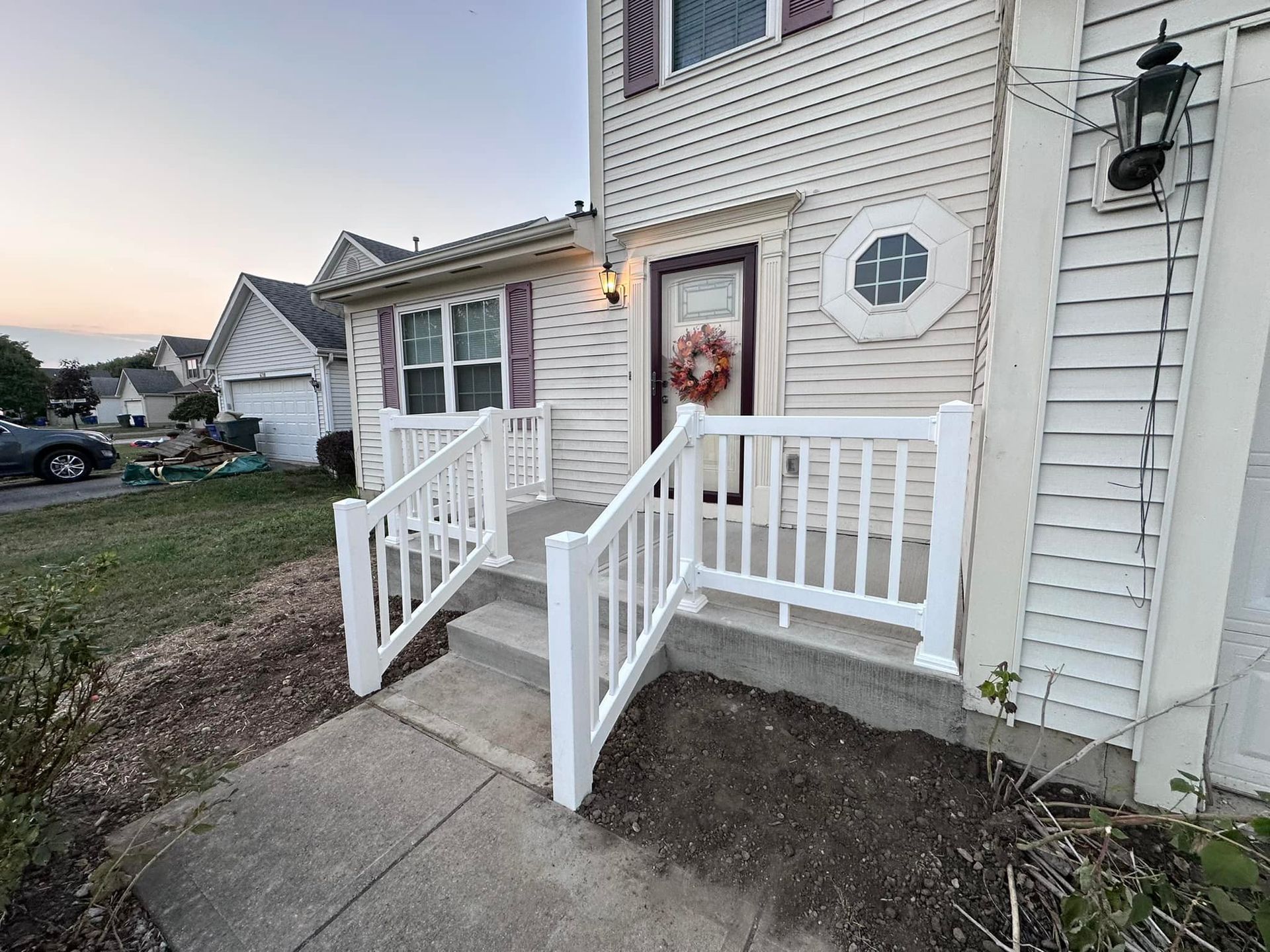 A white house with a white railing and stairs leading to the front door.