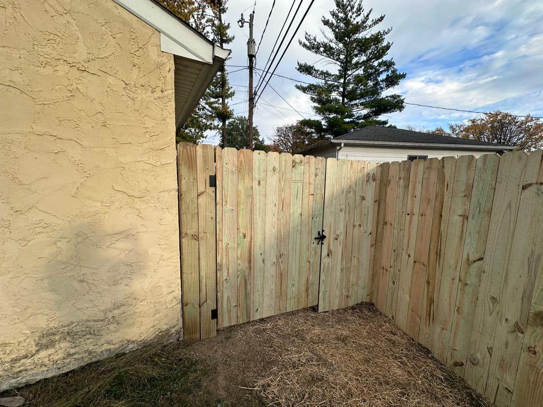 A wooden fence with a gate in the backyard of a house.