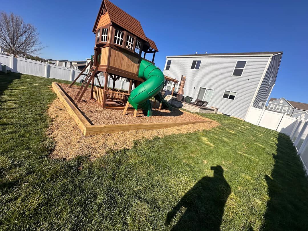 A playground with a slide and a tree house in the backyard of a house.