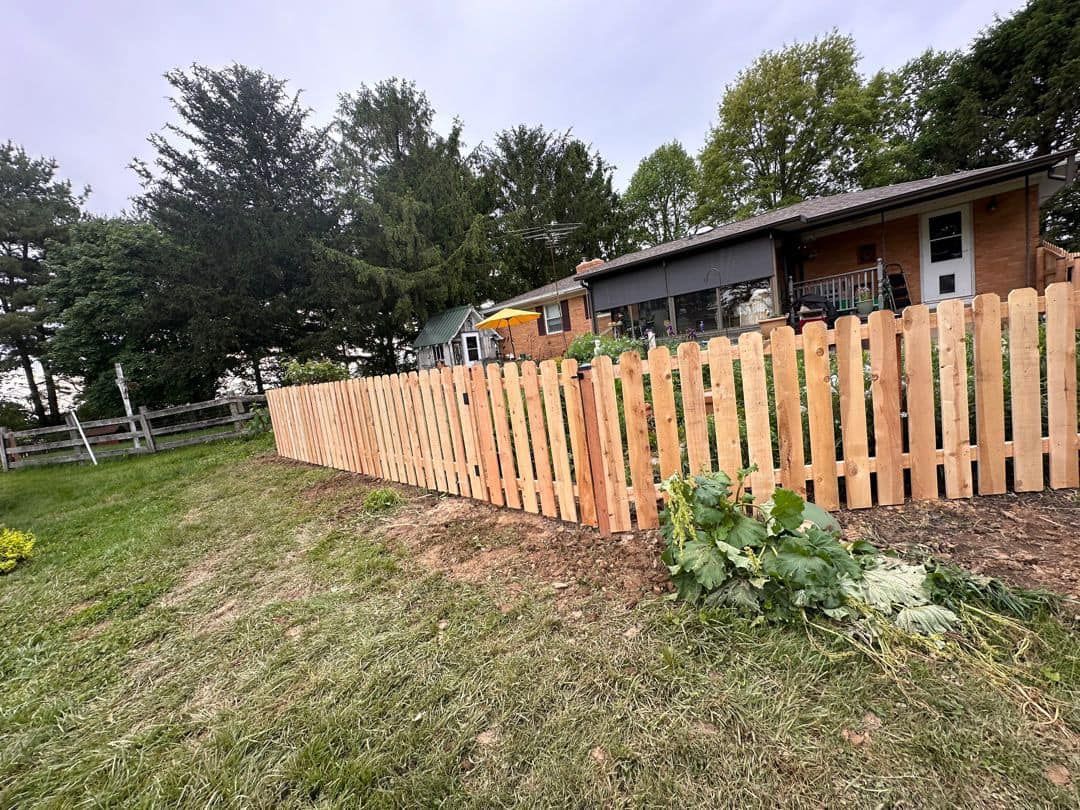 A wooden picket fence is in front of a house.
