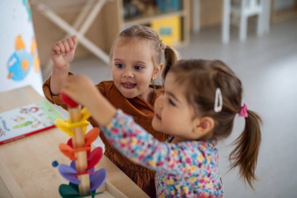 Two little girls are playing with a wooden toy.