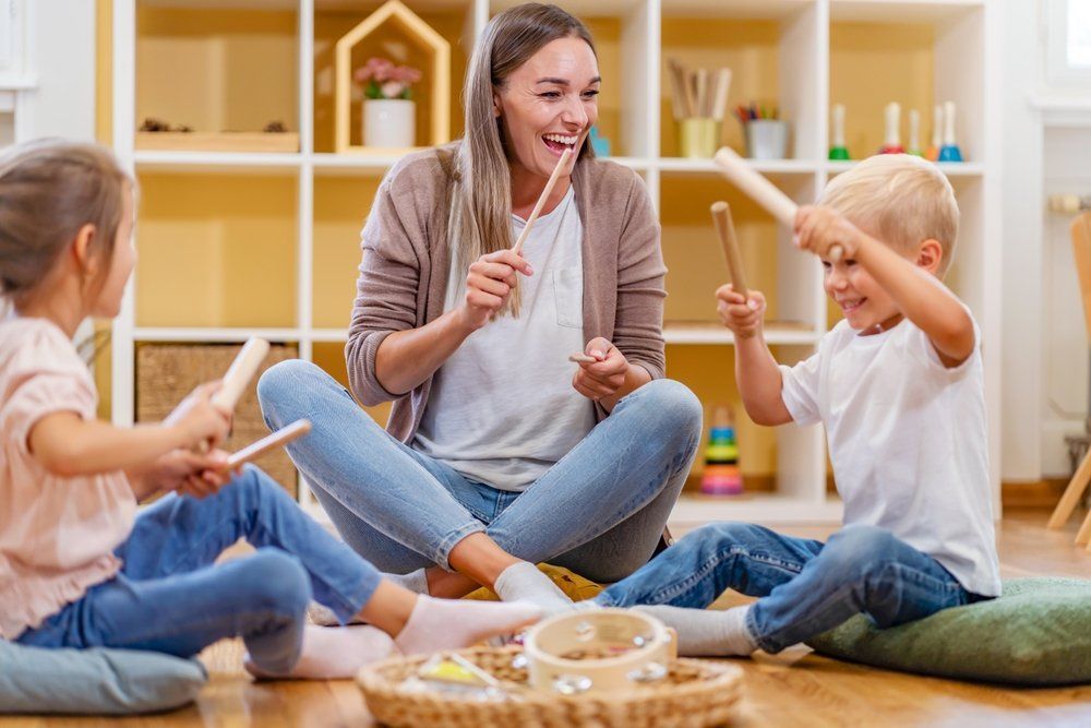 A woman and three children are sitting on the floor playing musical instruments.