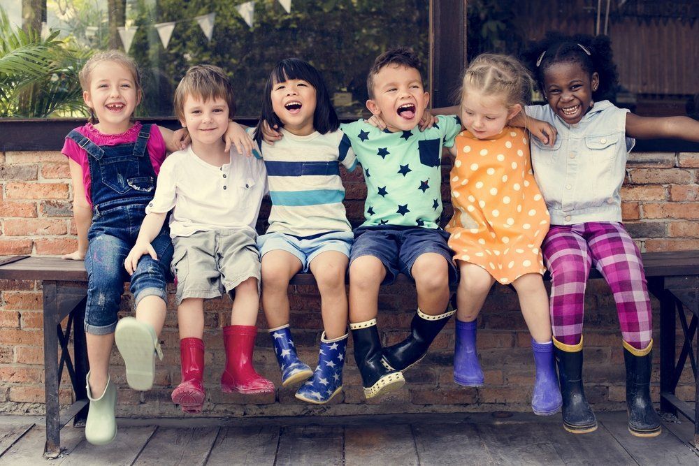 A group of children are sitting on a bench together.