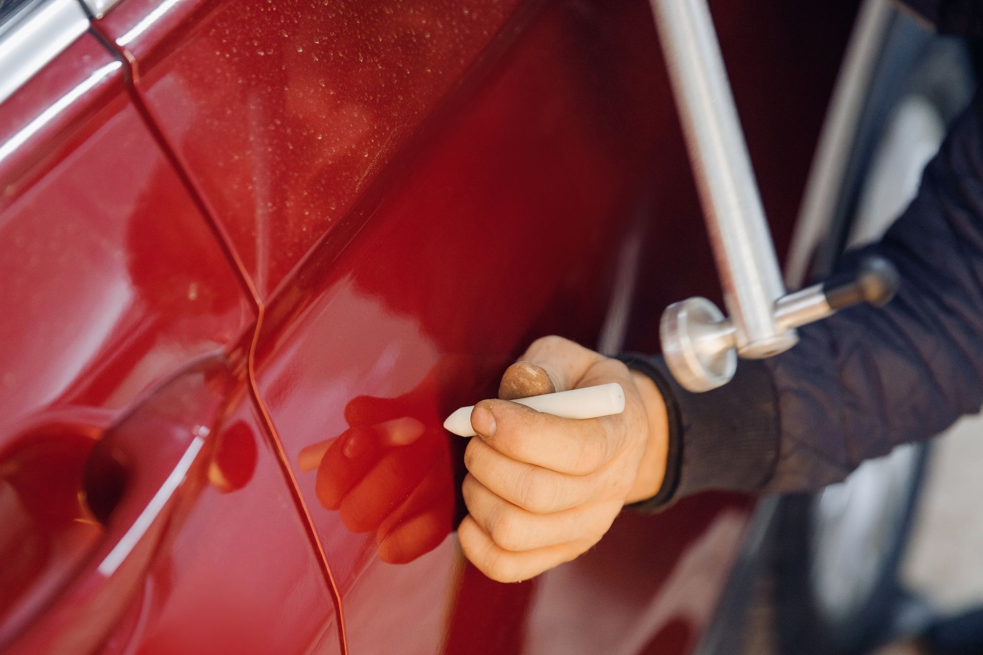 A person is using a tool to fix a car door.