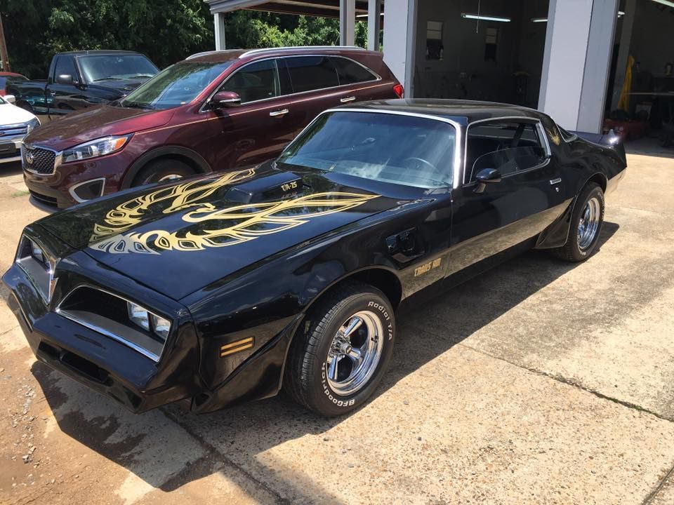 A black pontiac trans am is parked in a parking lot.