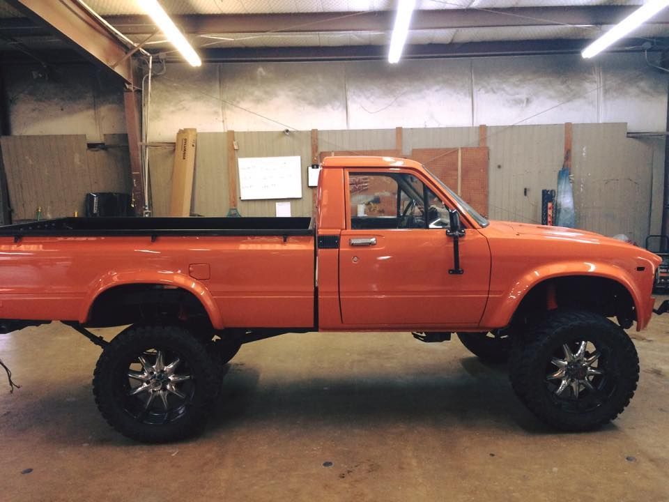 An orange truck with black wheels is parked in a garage