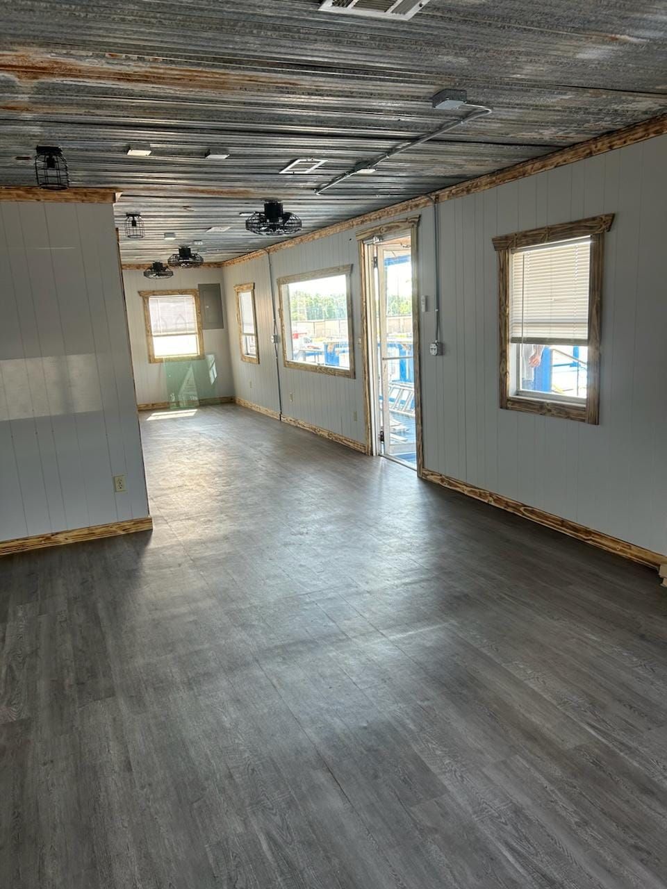 A large empty room with a wooden floor and a ceiling fan.