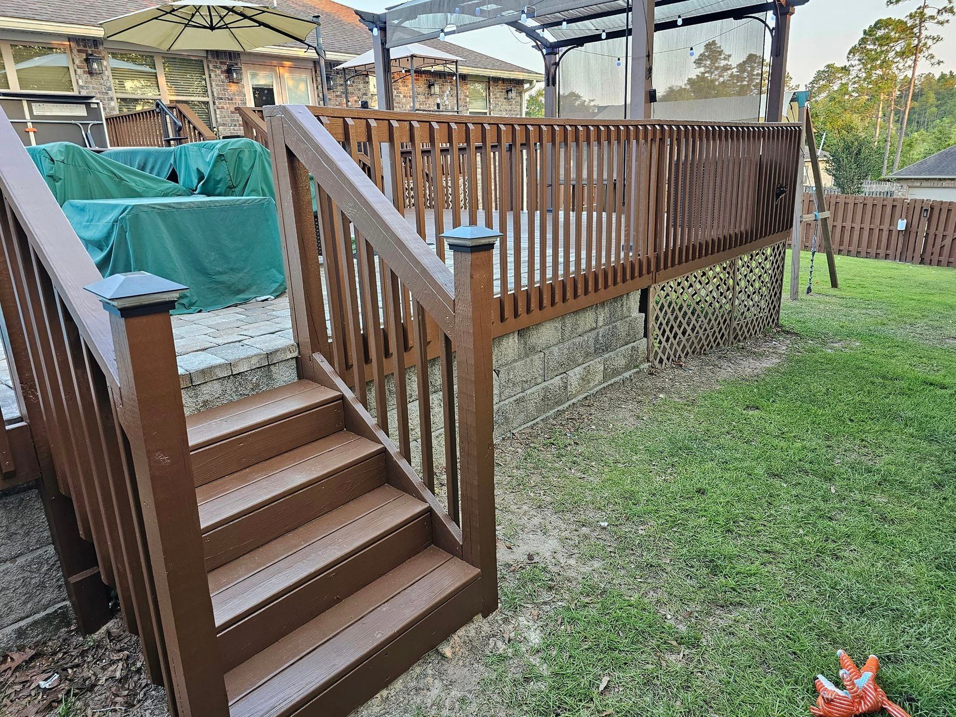 A wooden deck with stairs leading up to it in a backyard.