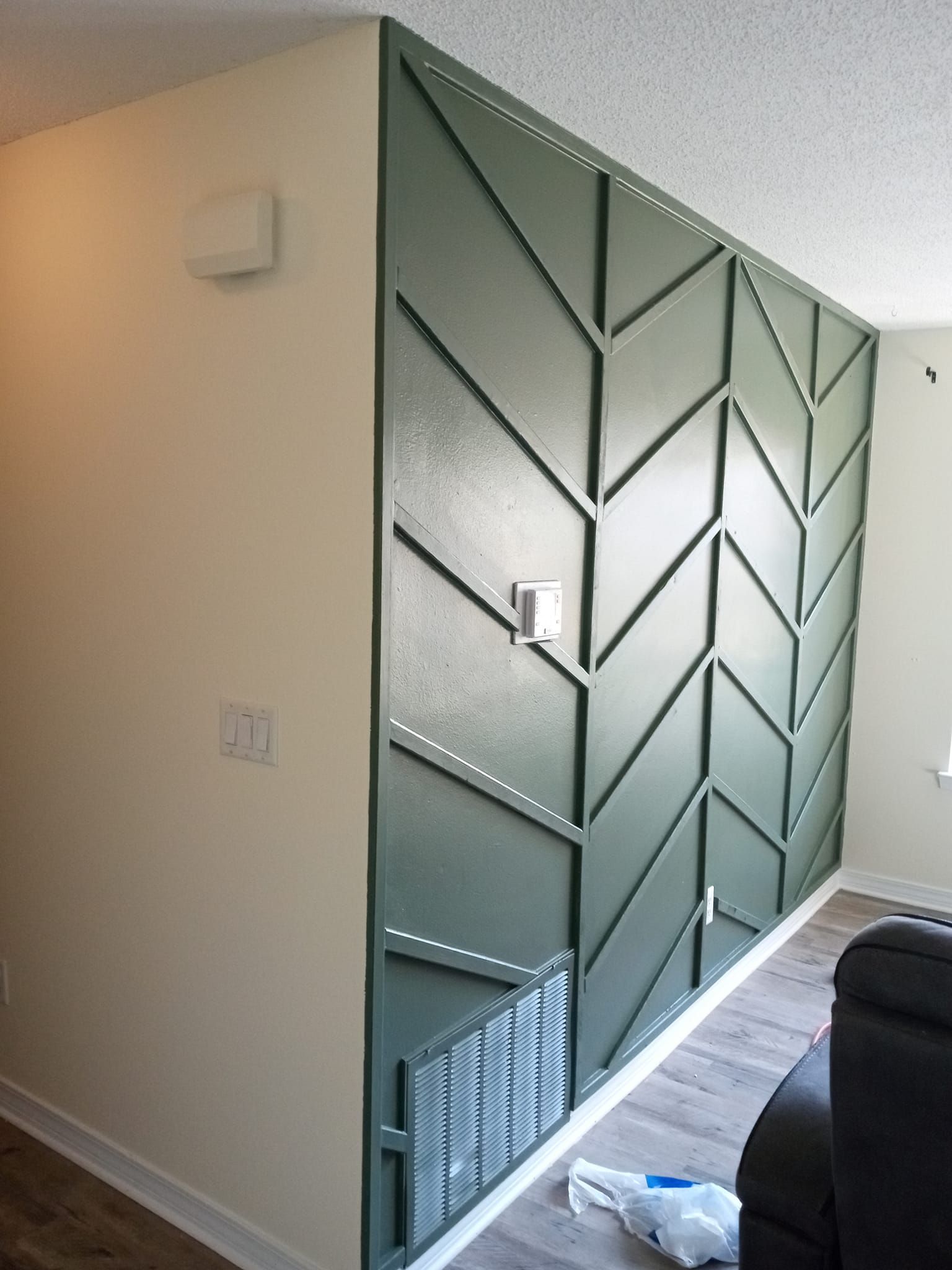 A living room with a green wall and a black couch.