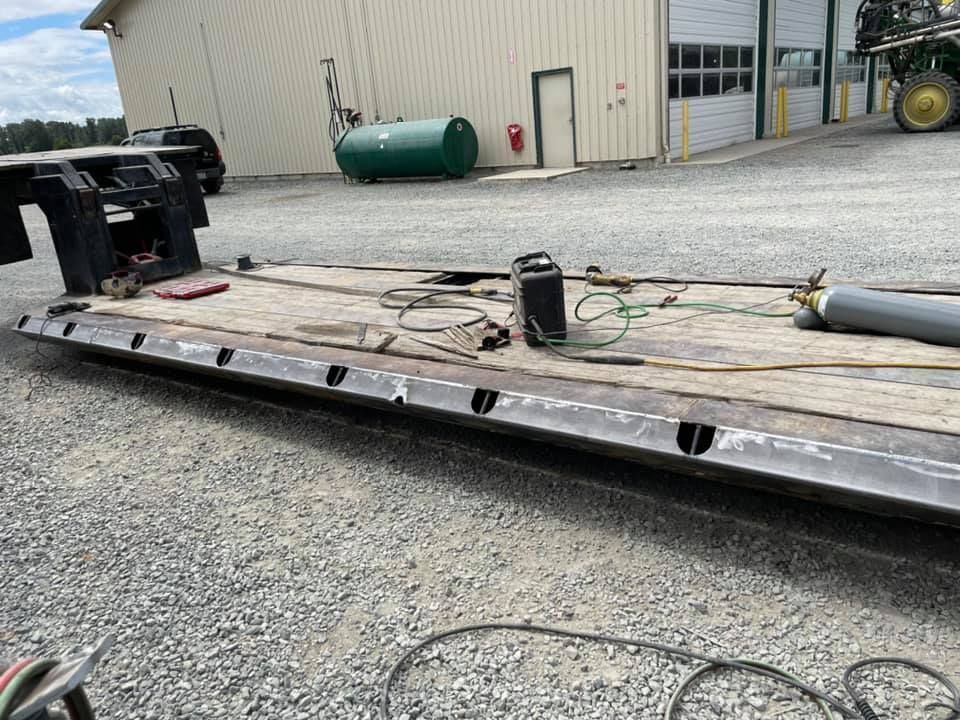 A trailer is sitting in a gravel lot in front of a building.