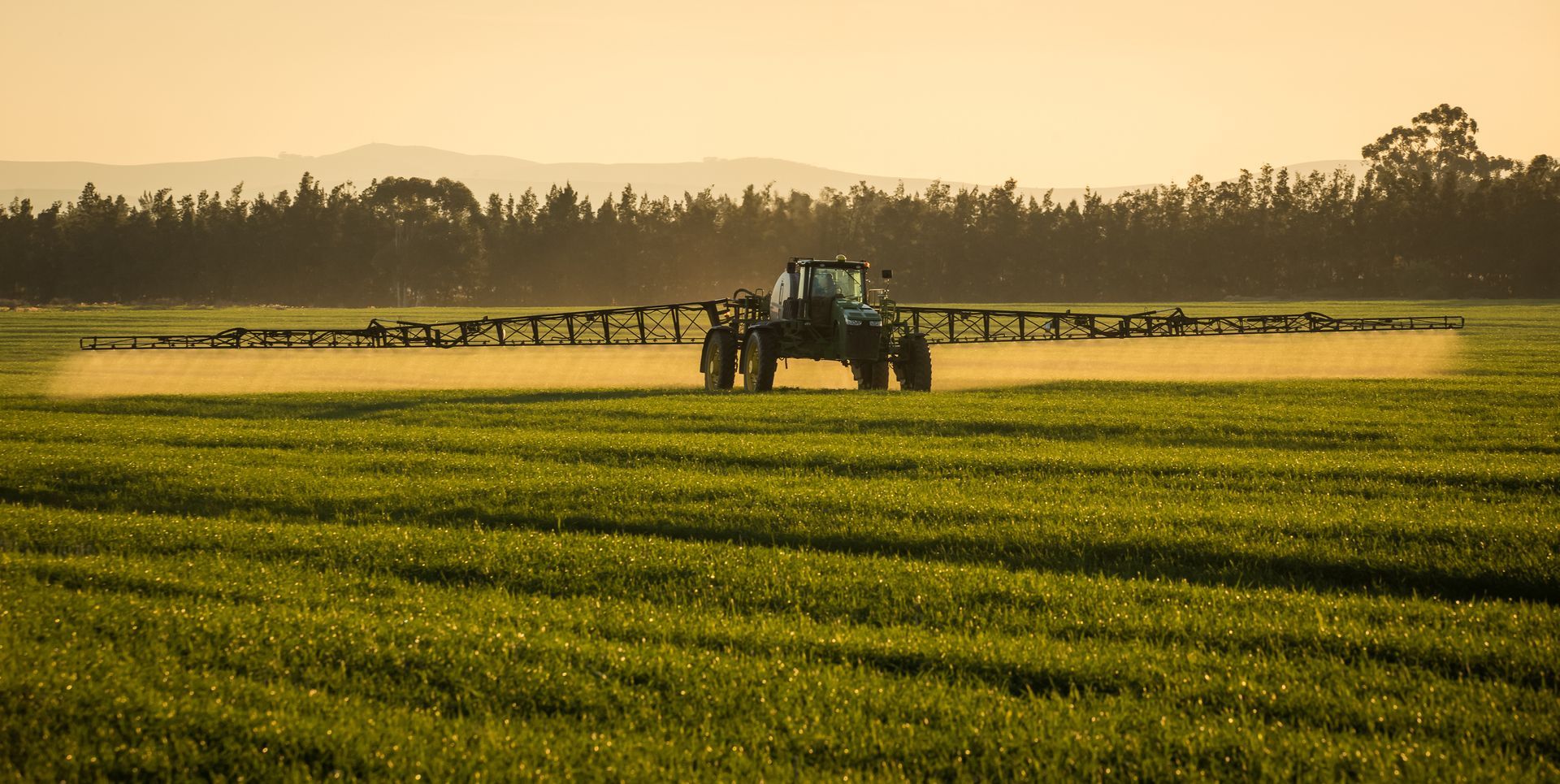 Trator estacionado em um campo agrícola com céu parcialmente nublado