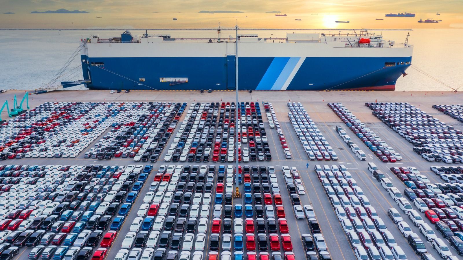 Um grande navio está atracado em um grande estacionamento cheio de carros.