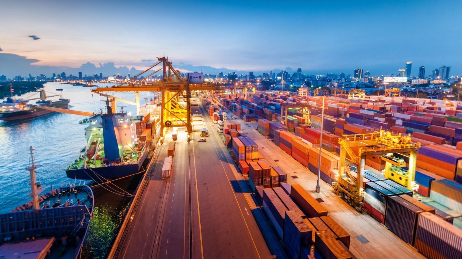 An aerial view of a cargo ship docked in a harbor at night.