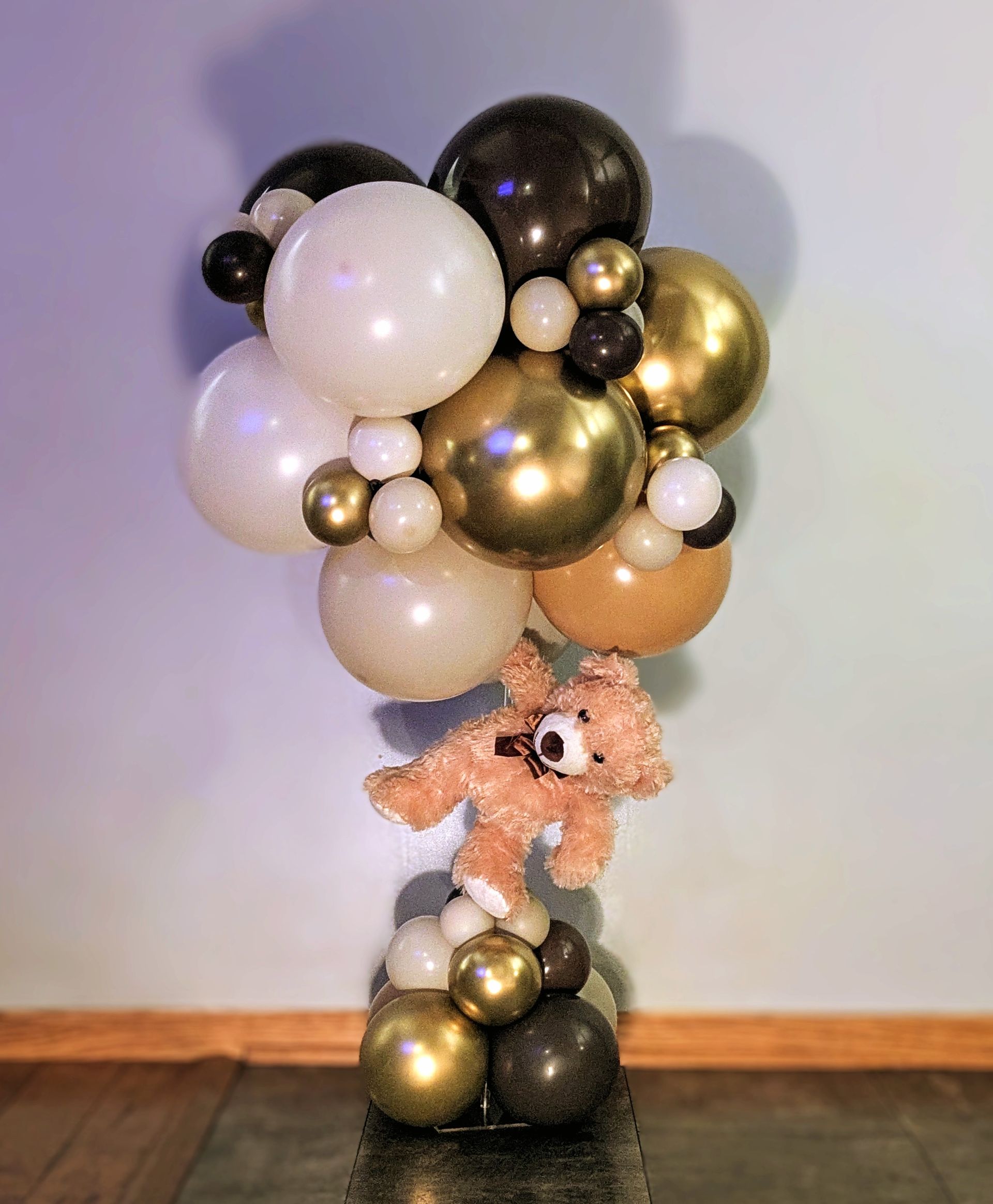 A balloon arrangement featuring white, gold, and black balloons 