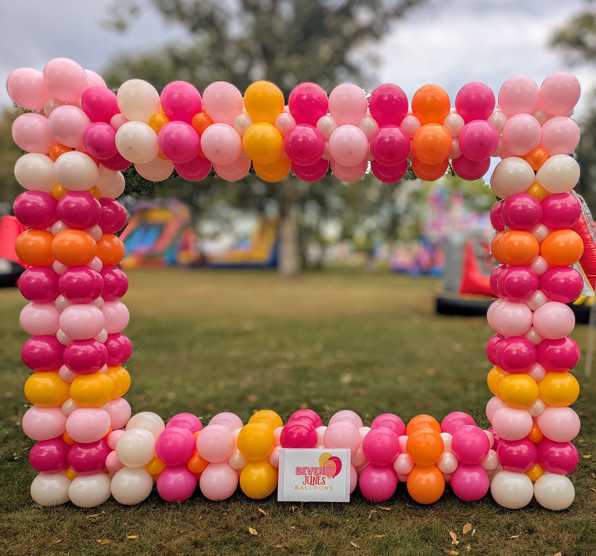 A colorful balloon archway in pink, orange, and yellow 