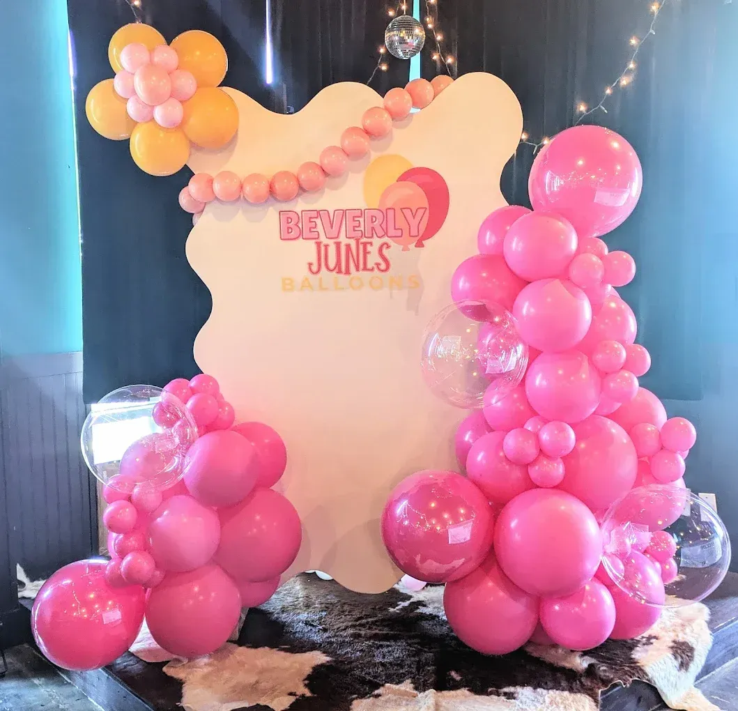 Pink and yellow balloon decor with a sign that reads 