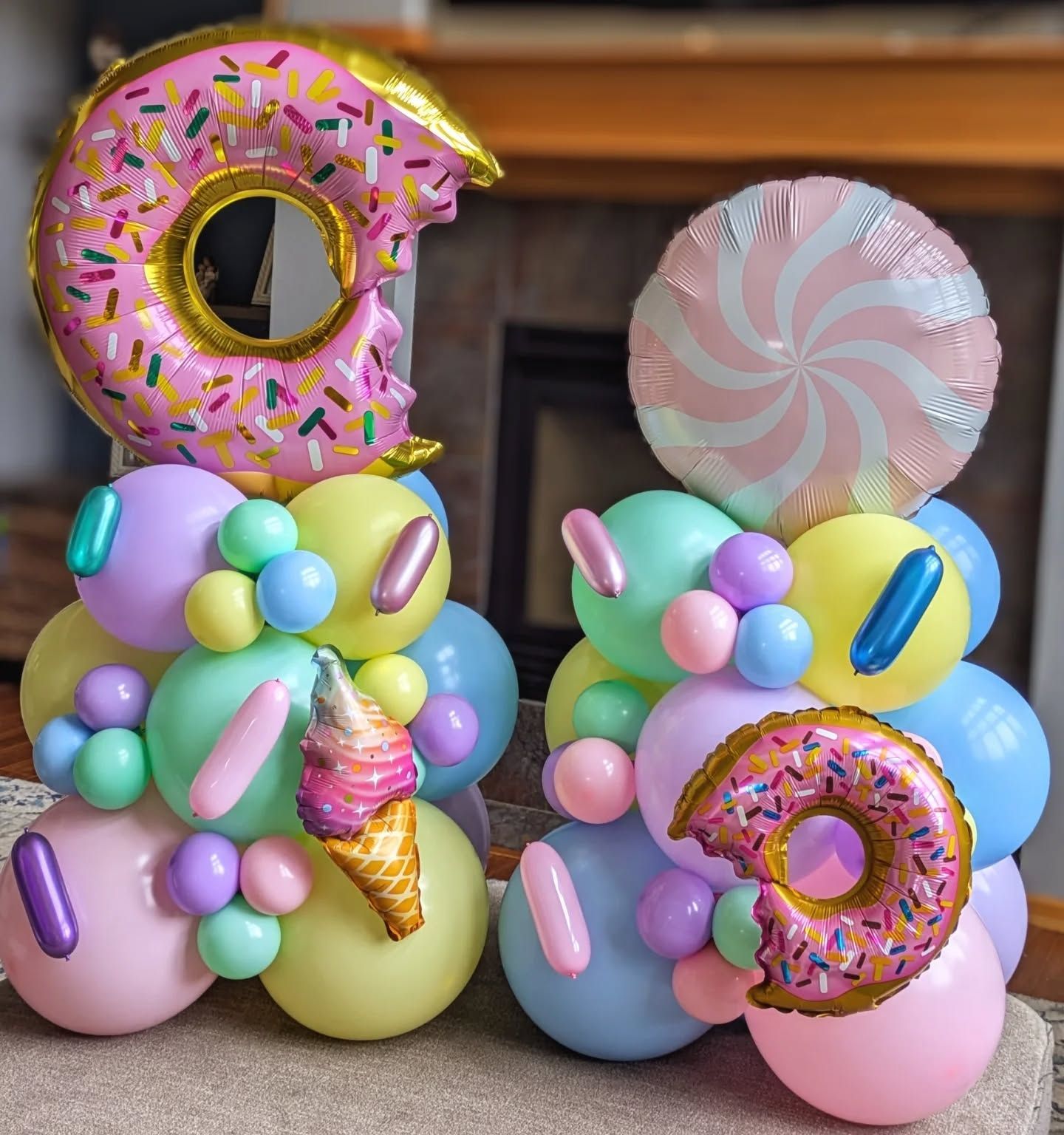 A bunch of balloons with donuts , ice cream cones , and lollipops on them.