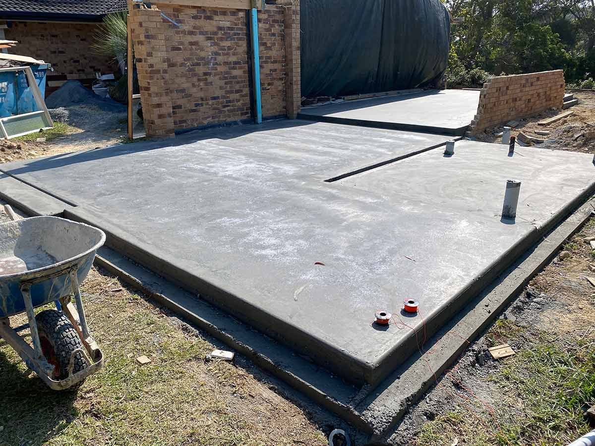 A Wheelbarrow Is Sitting on The Ground Next to A Concrete Floor — Shaka Concreting In South Golden Beach, NSW