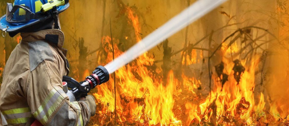 Firefighter spraying water on flames.