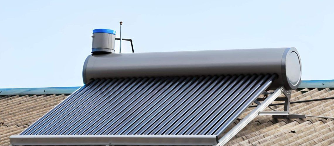 Solar water heater on a rooftop, blue tank, black tubes, and blue sky.