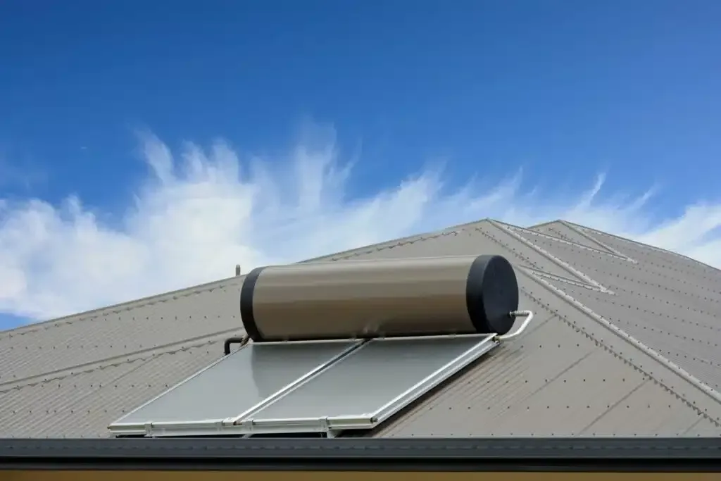 Solar water heater on a rooftop against a bright blue sky.