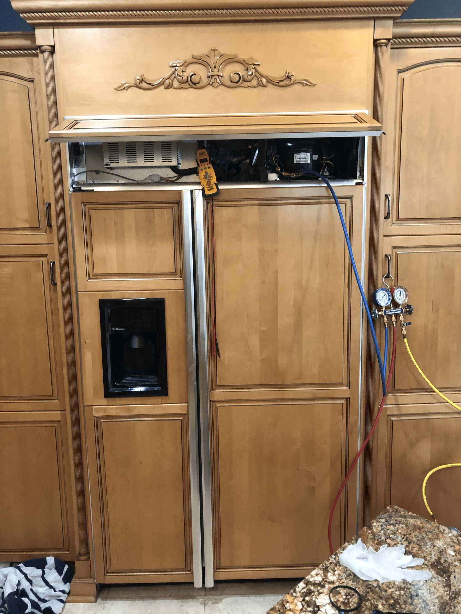 A refrigerator is being installed in a kitchen with wooden cabinets.