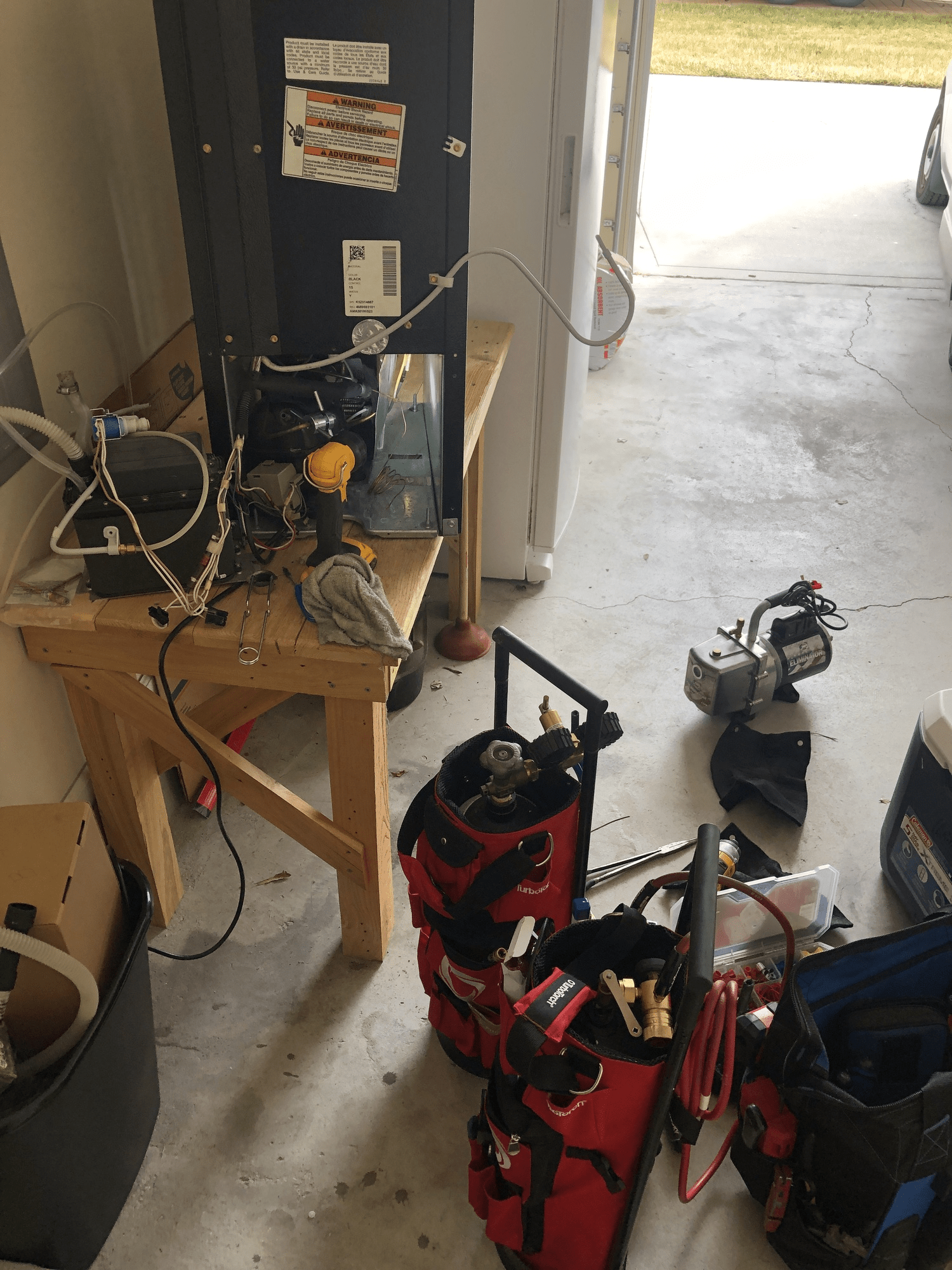 A messy room with a refrigerator and tools on the floor
