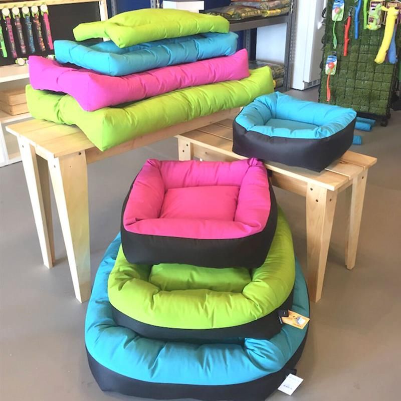A bunch of colorful dog beds are stacked on top of each other