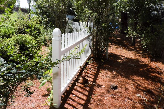 A White Picket Fence Surrounds a Lush Green Garden — Shaun Steenson Building Services in Townsville, QLD