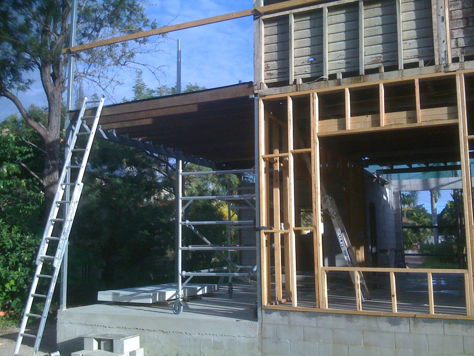 Partially Built House with Ladders and Scaffolding Under Construction Outdoors — SS Building Services in Townsville, QLD