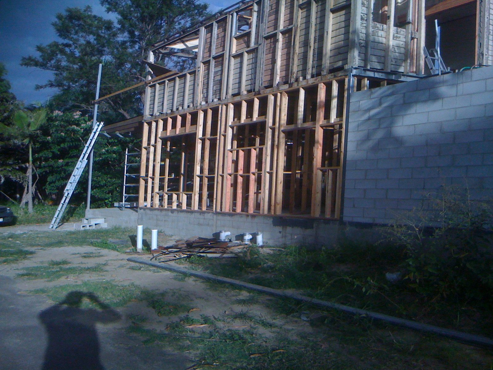 Partially Built Wooden House Beside a Gray Cinderblock Wall — SS Building Services in Townsville, QLD