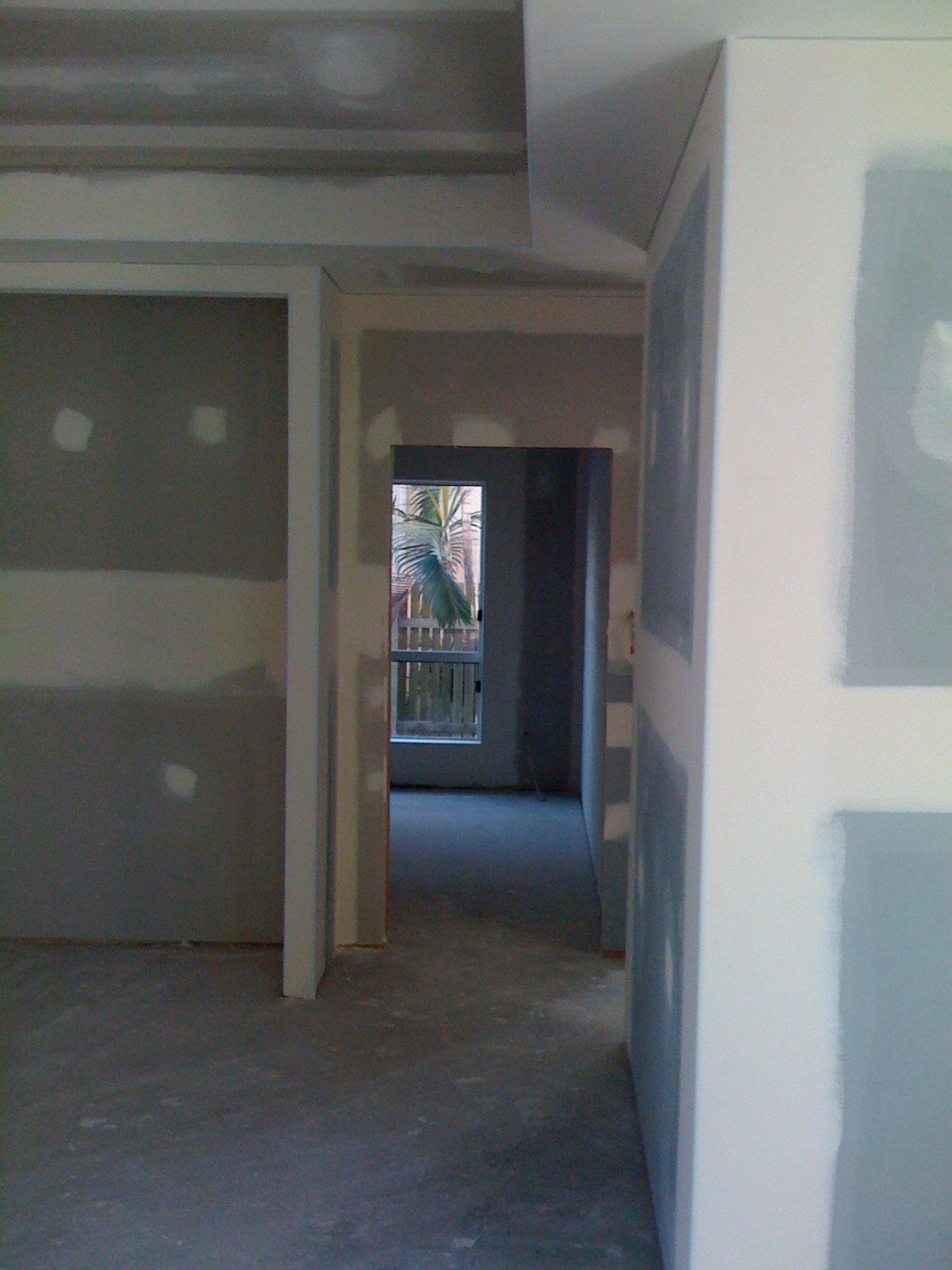 Empty Unfinished Hallway with Drywall Leading to A Bright Doorway — SS Building Services in Townsville, QLD