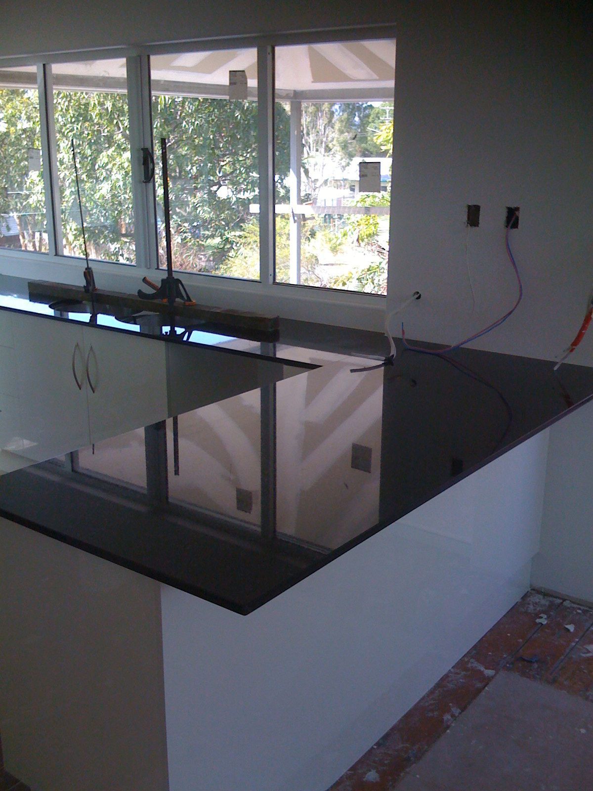Modern Kitchen with Glossy Black Countertop and Large Windows — SS Building Services in Townsville, QLD