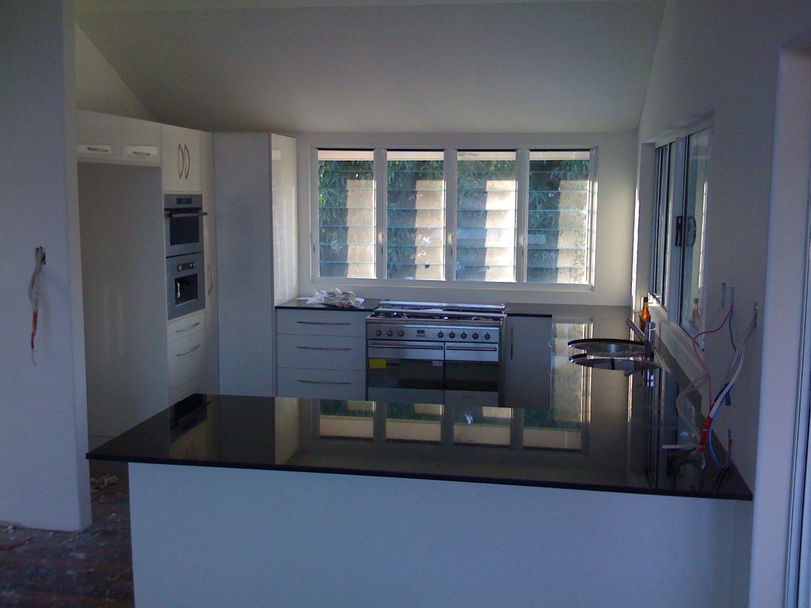 Modern Kitchen with White Cabinets and Black Island Countertop — SS Building Services in Townsville, QLD