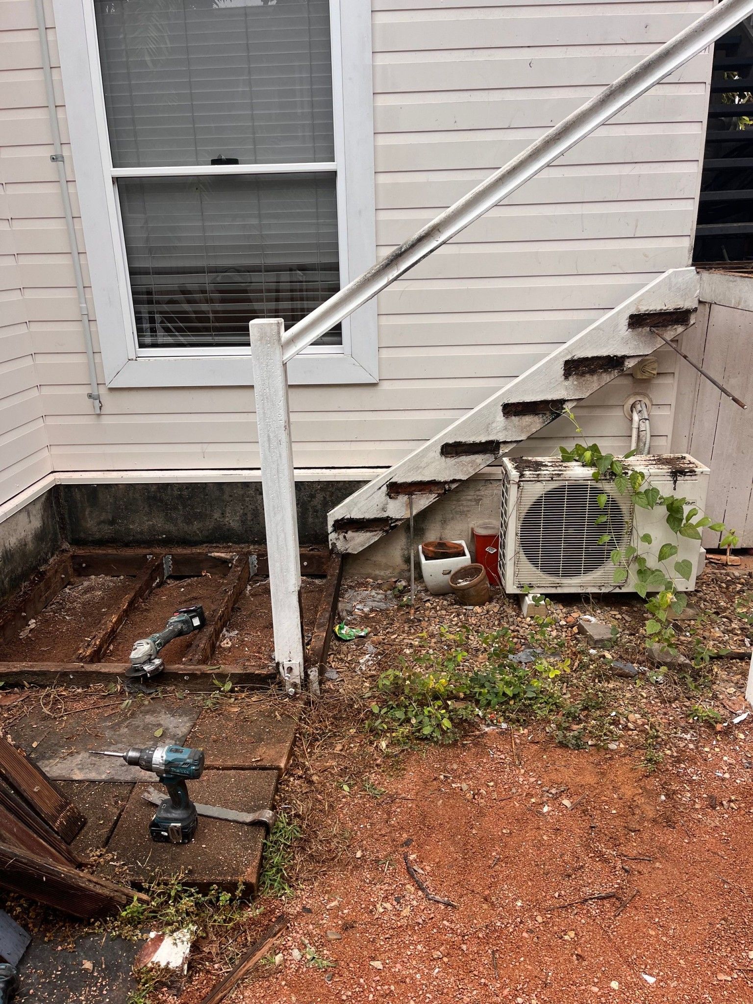A weathered outdoor staircase with handrail, leading up to a white building.  — Shaun Steenson Building Services in Townsville, QLD