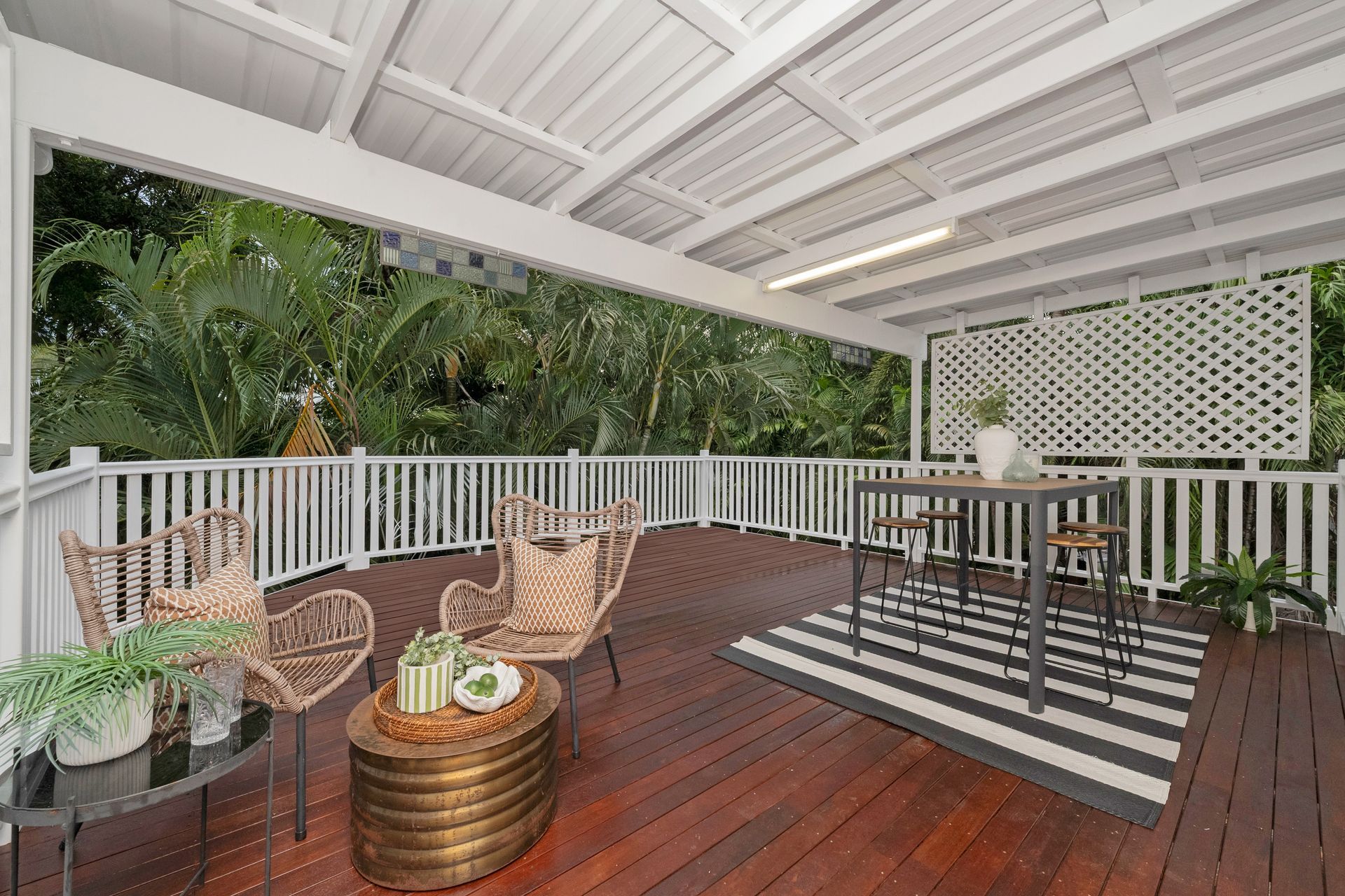 Covered Patio with Wicker Chairs and Lush Tropical Greenery Beyond the Railing — SS Building Services in Townsville, QLD