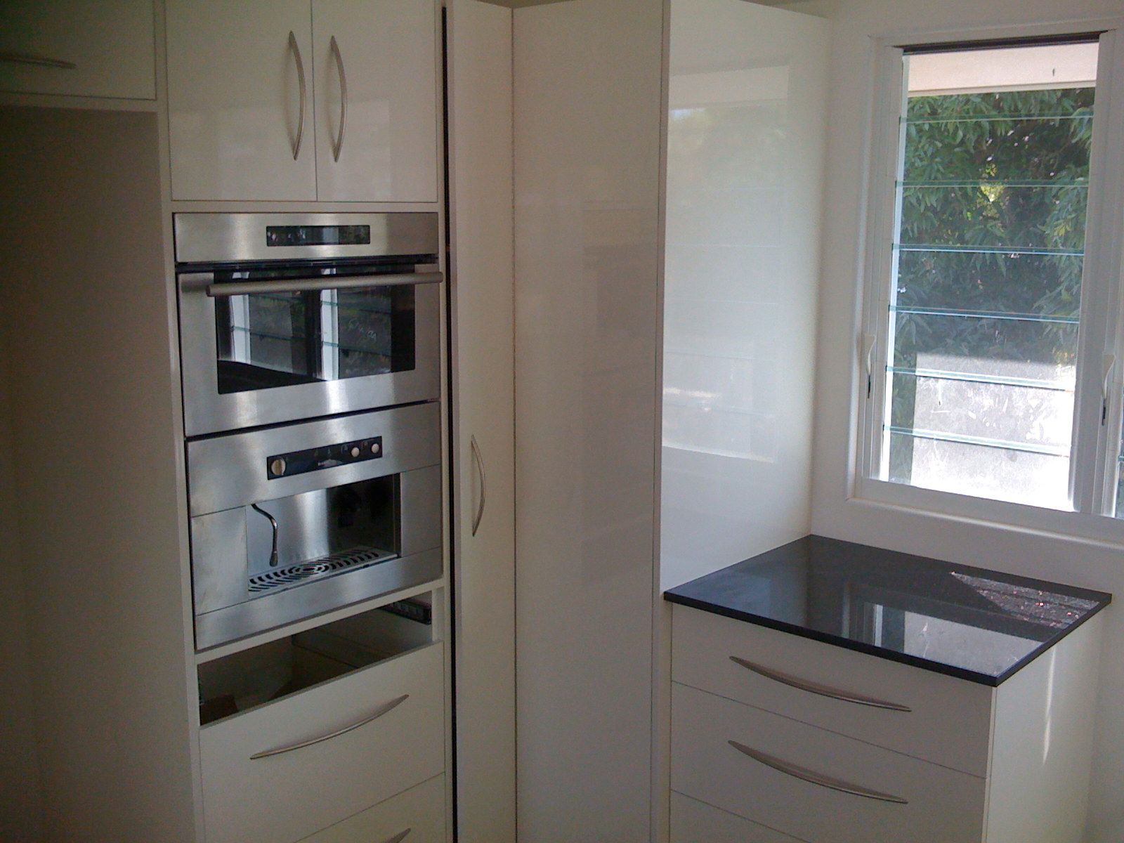 Modern White Kitchen with Built In Oven and Black Countertop — SS Building Services in Townsville, QLD