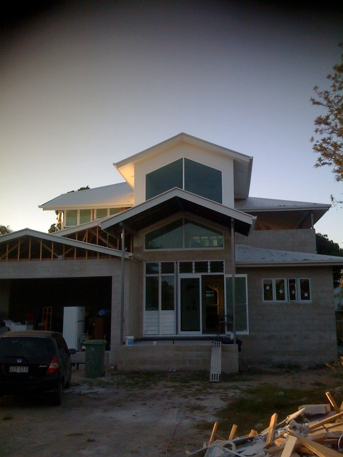 New House Under Construction at Dusk with Exposed Framing and A Car Parked in Front — SS Building Services in Townsville, QLD