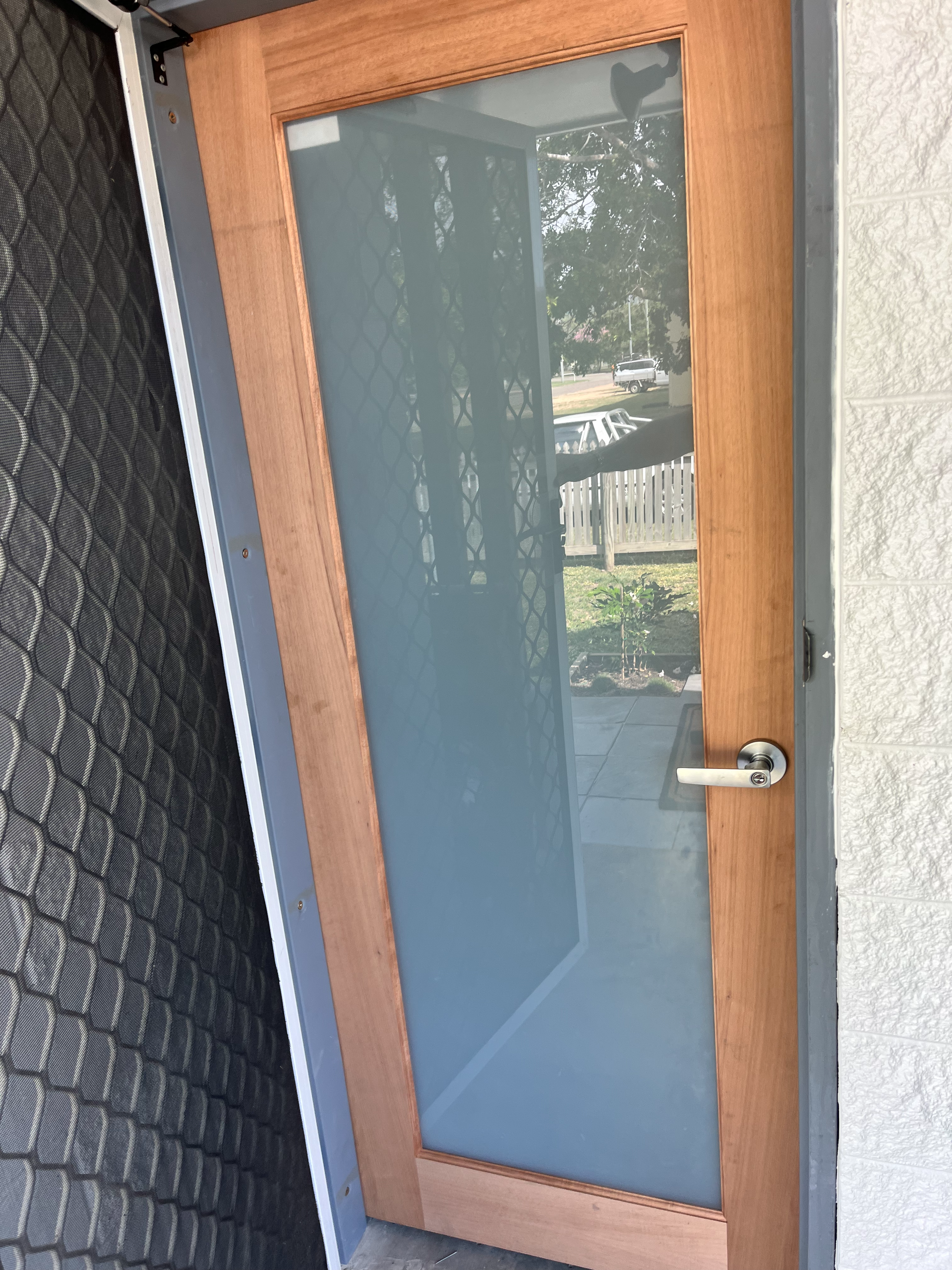 A Man is Fixing a Door With a Drill and Glue — Shaun Steenson Building Services in Townsville, QLD