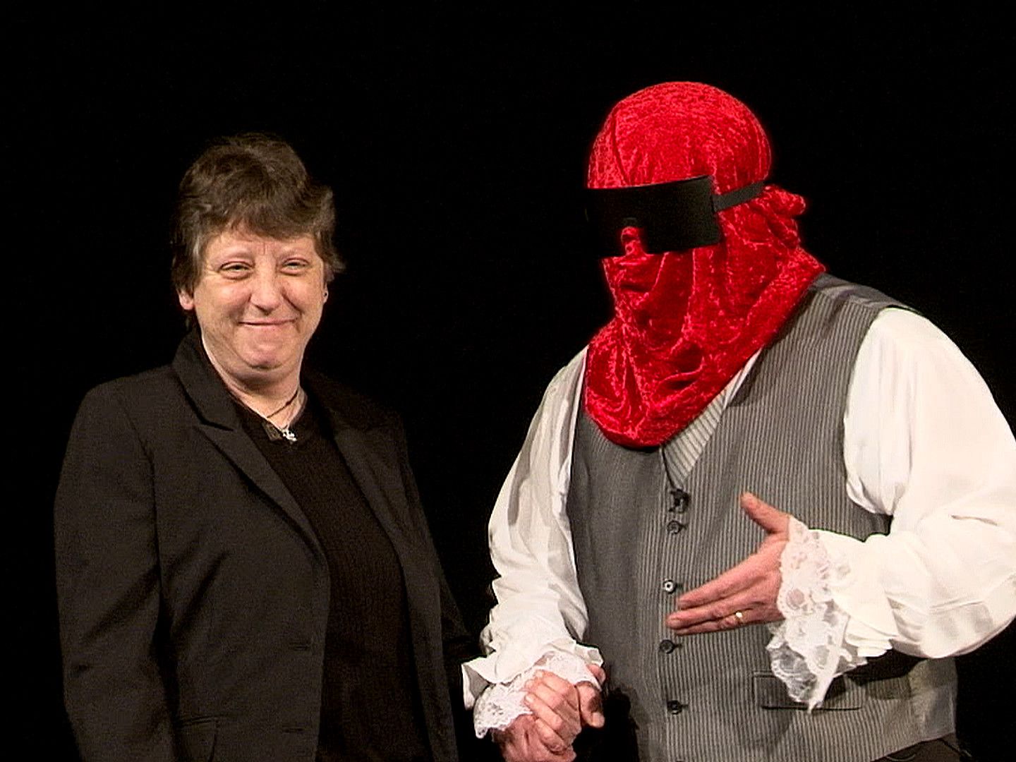 A man wearing a red mask is shaking hands with a woman