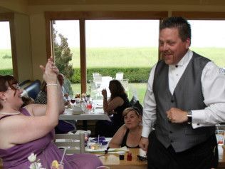 A woman in a purple dress is sitting at a table while a man performs a magic trick.