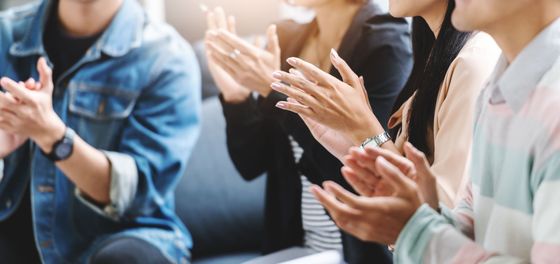 A group of people are clapping their hands together while sitting on a couch.