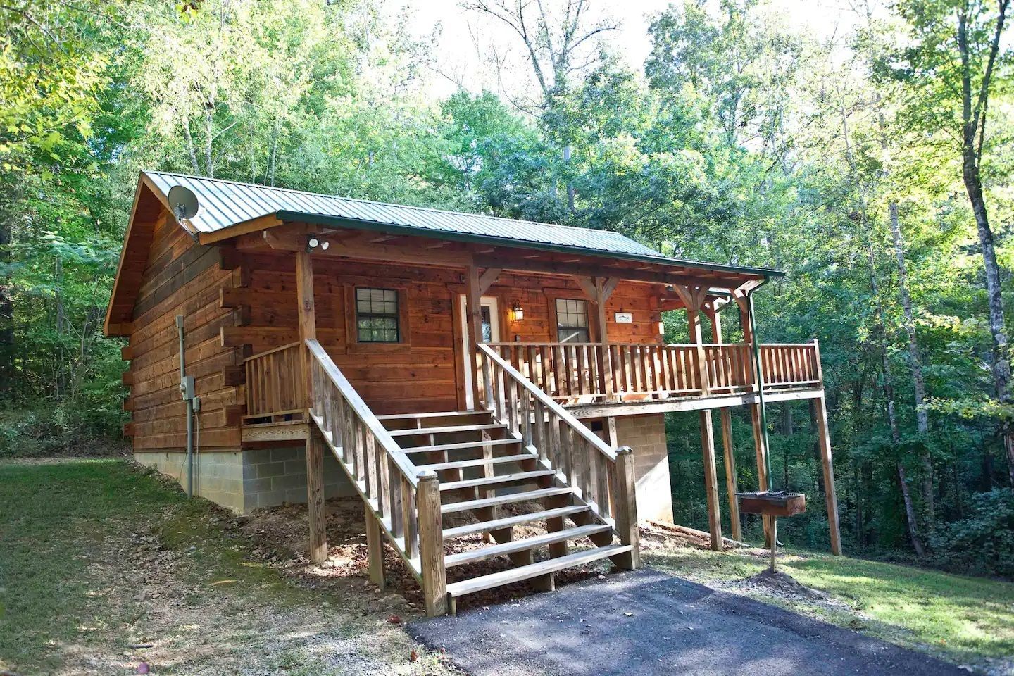 Wooden cabin with front porch and stairs in a wooded setting