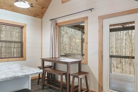 Cozy sunroom with wood-paneled walls, large windows, and a small table with stools