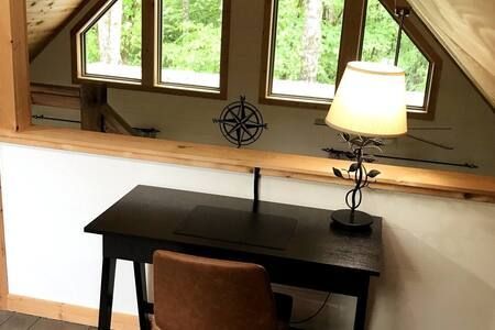 Home office desk by windows with a lamp and chair in a loft room